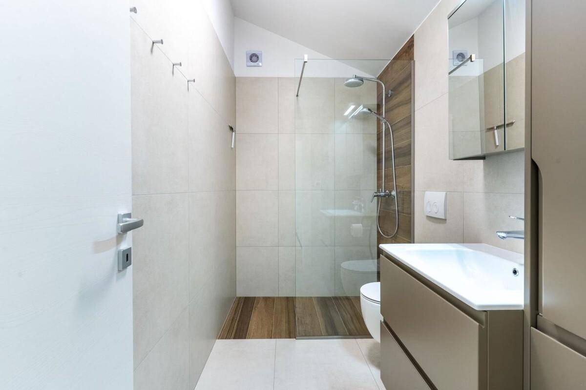 Modernes Badezimmer mit begehbarer Dusche, Wand-WC und eleganten Fliesen.