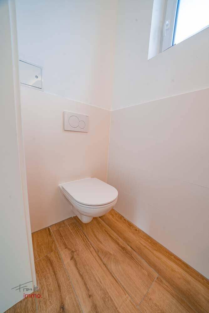 Helles Gäste-WC mit wandhängender Toilette und Fenster für natürliche Belüftung.