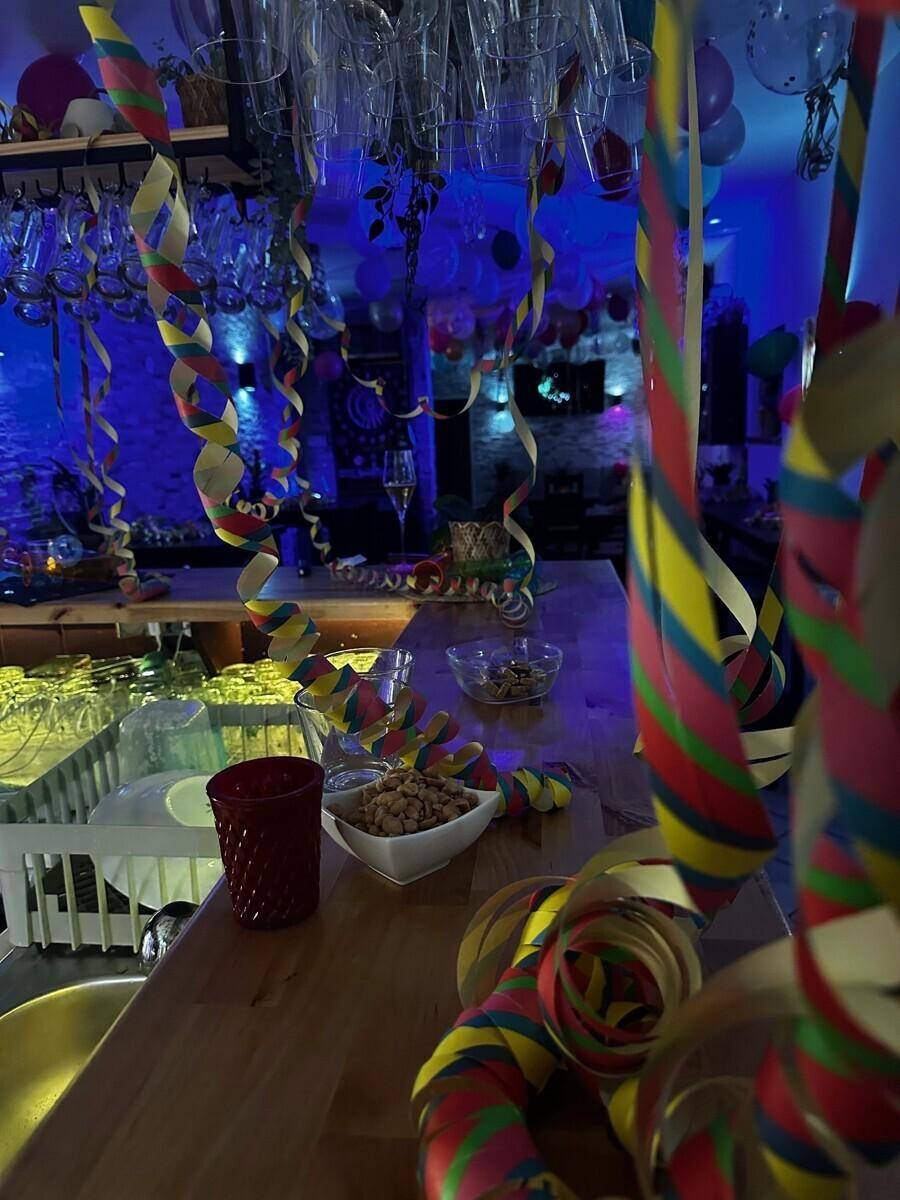 Nahaufnahme des Holztresens einer Bar, festlich geschmückt mit Luftschlangen und blauer Beleuchtung.