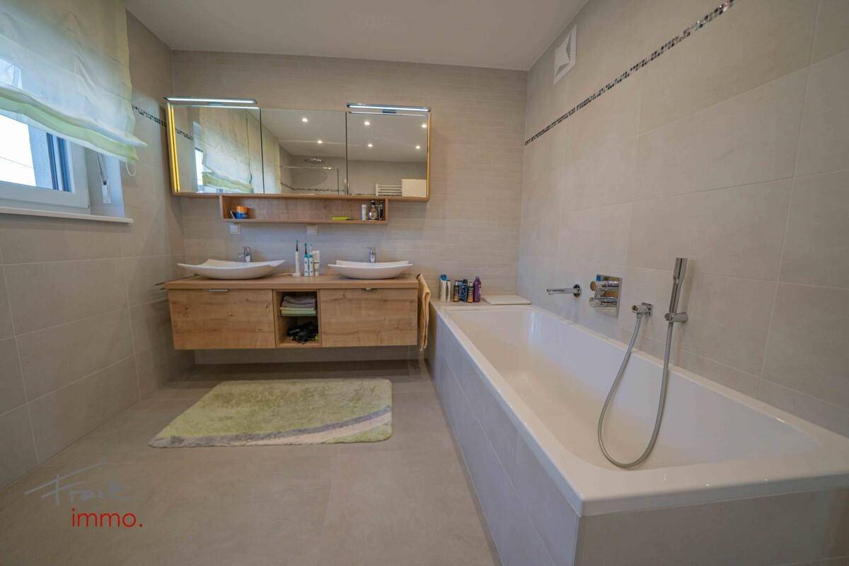 Geräumiges Badezimmer mit Badewanne, Doppelwaschbecken und hellen Fliesen.