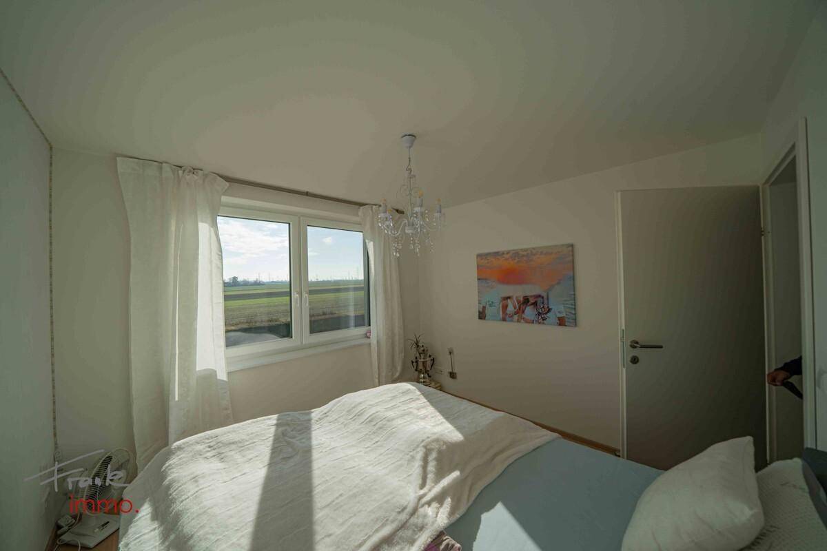 Helles Schlafzimmer mit Parkettboden und weitem Blick ins Grüne.