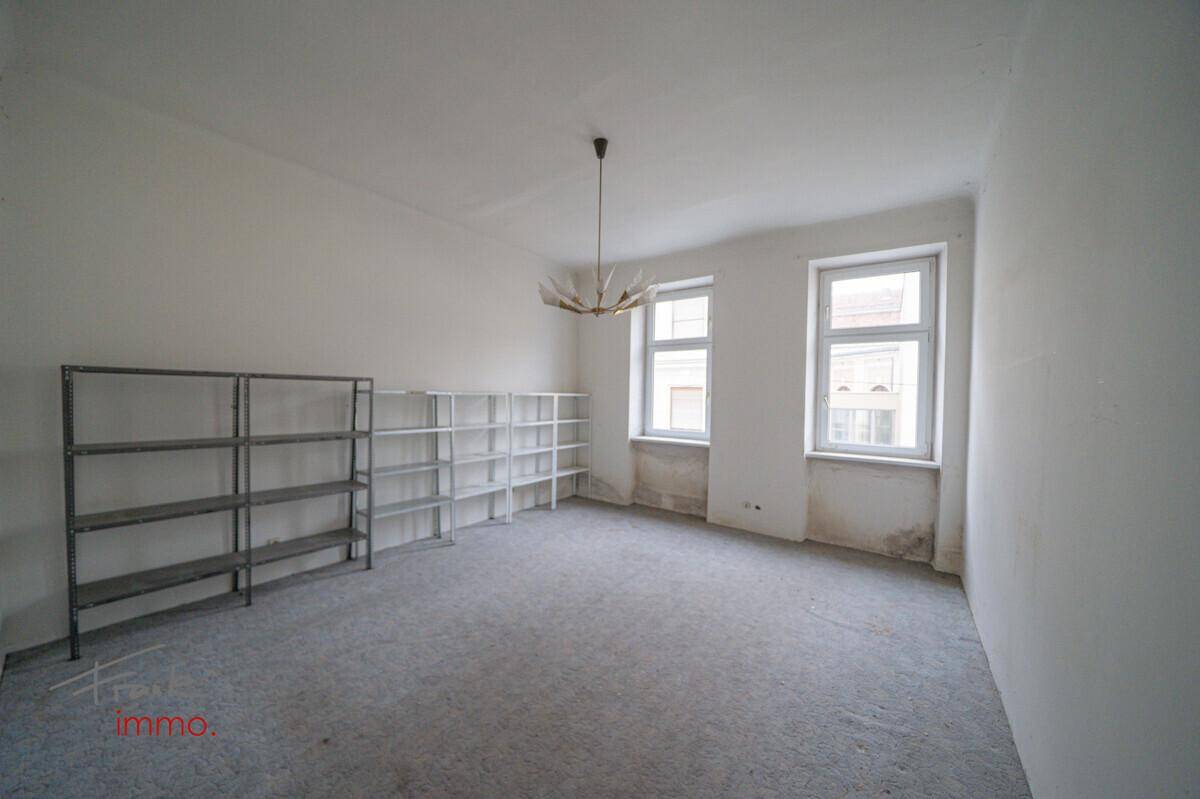 Geräumiger Raum mit Regalen und zwei Fenstern, ideal als Büro oder Arbeitszimmer.