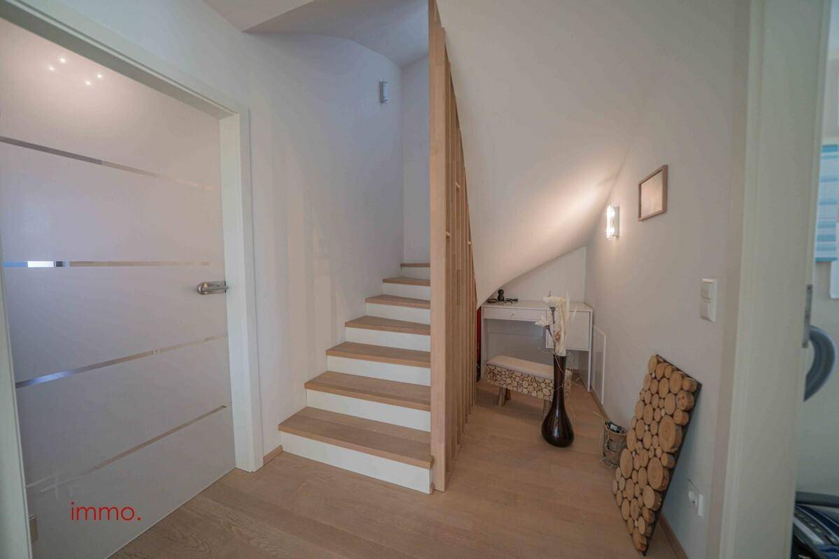 Treppenaufgang mit Holzstufen und hellem Parkettboden, führt in die obere Etage.