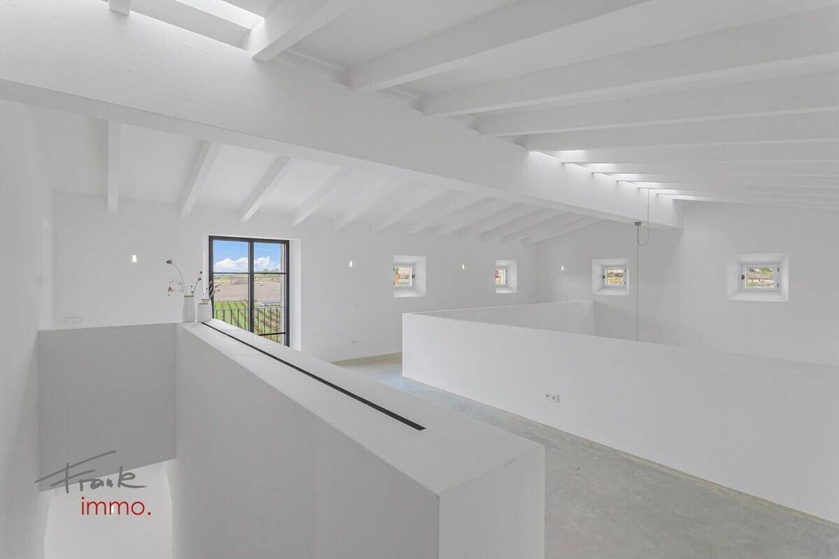 Heller offener Bereich im Obergeschoss mit hoher Decke und sichtbaren Balken, ideal als Galerie.