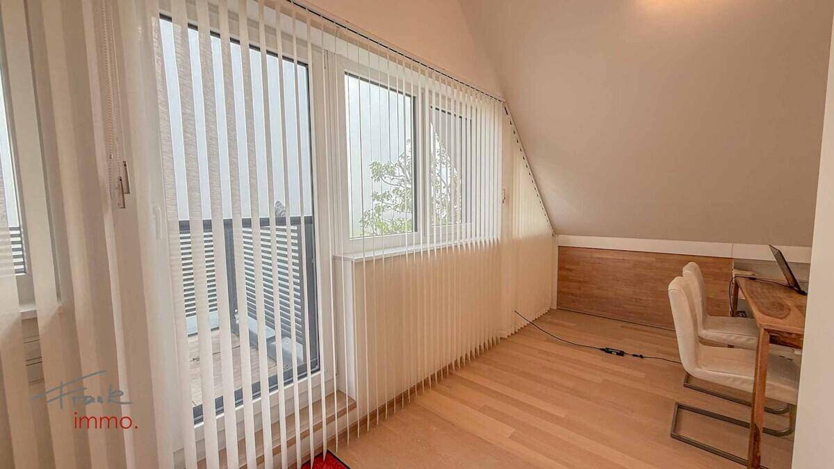 Heller Dachbodenbereich mit großen Fenstern und Holzboden, ideal als Arbeitszimmer.
