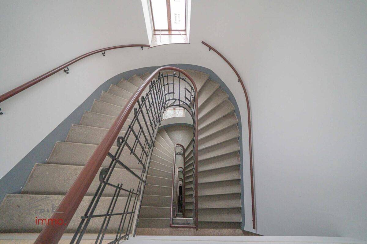 Elegantes Wendeltreppenhaus mit schmiedeeisernem Geländer und natürlichem Lichteinfall von oben.