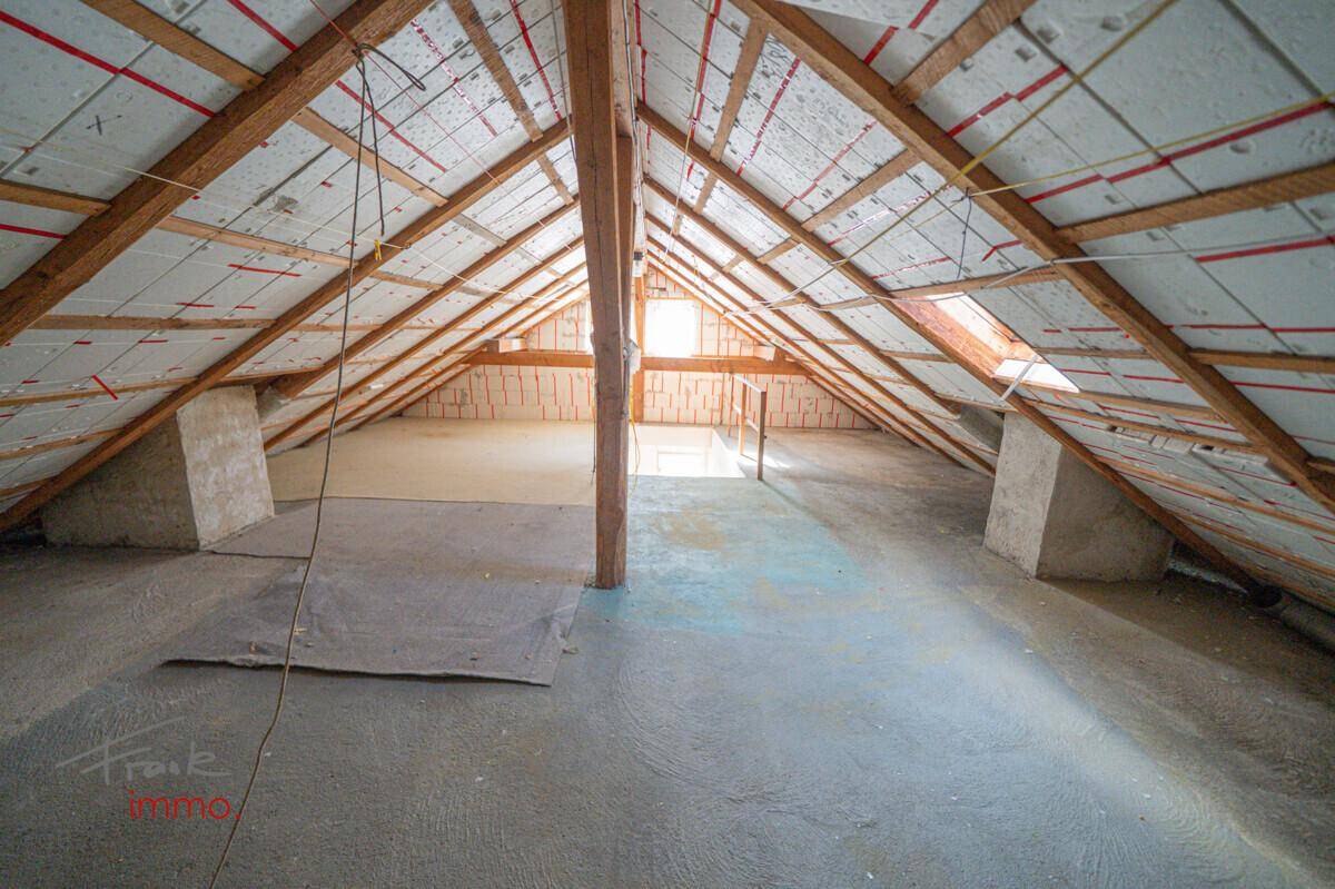 Geräumiger Dachboden mit sichtbarer Holzkonstruktion und einem kleinen Fenster, ideal zum Ausbau.