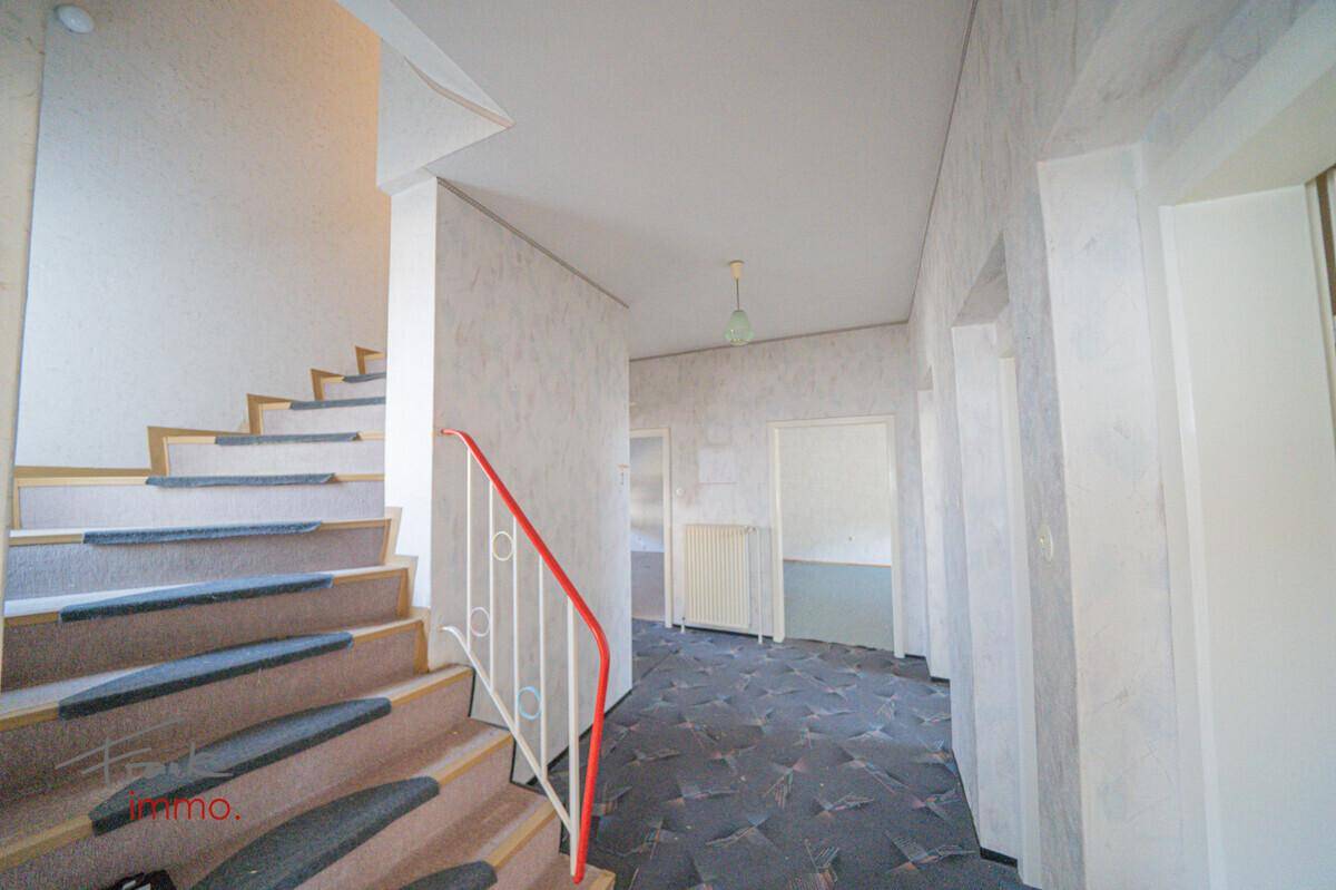 Treppenhaus mit Teppichstufen und Geländer, das zu den oberen Etagen des Hauses führt.