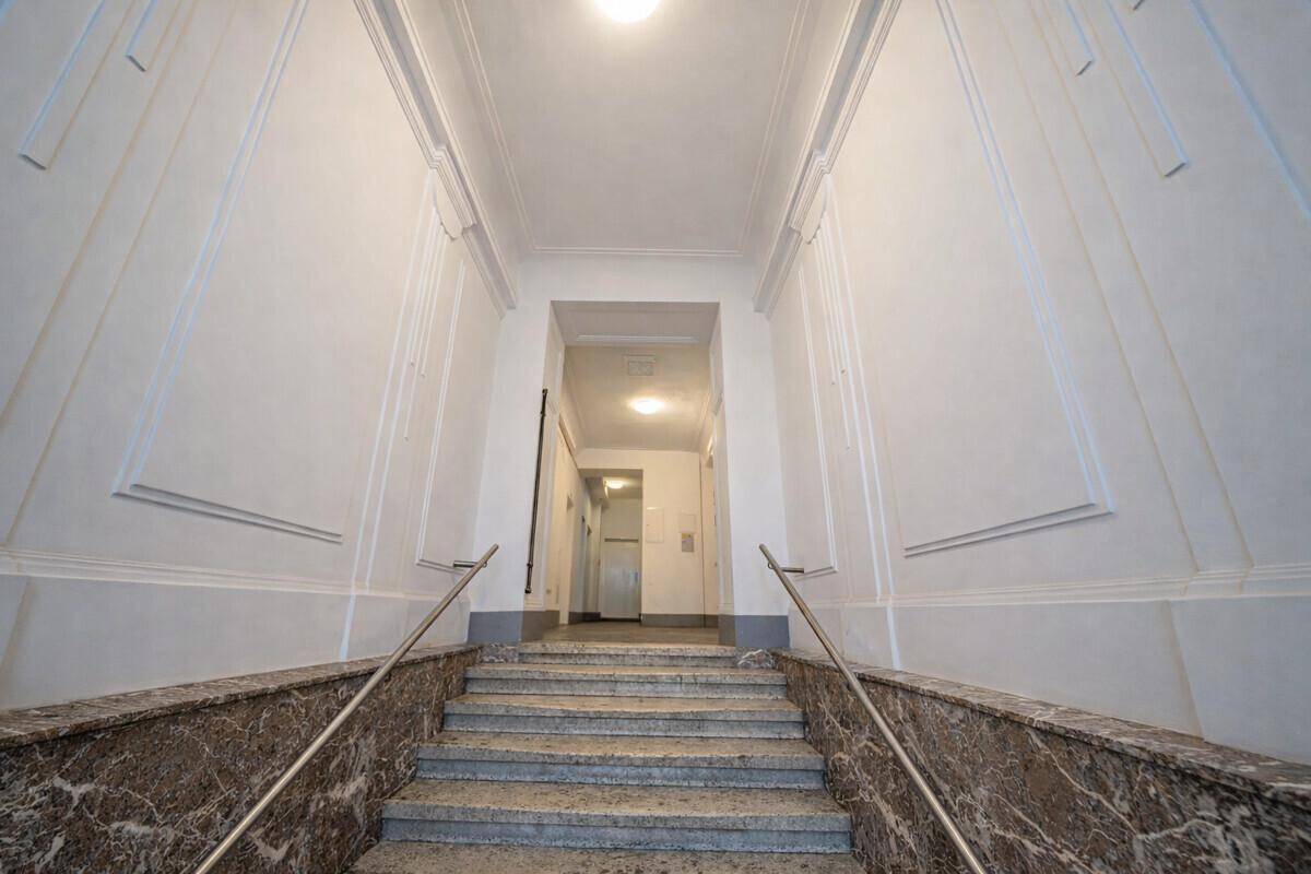Repräsentatives Treppenhaus mit Marmorverkleidung und Stuckelementen, typisch für Altbauten.