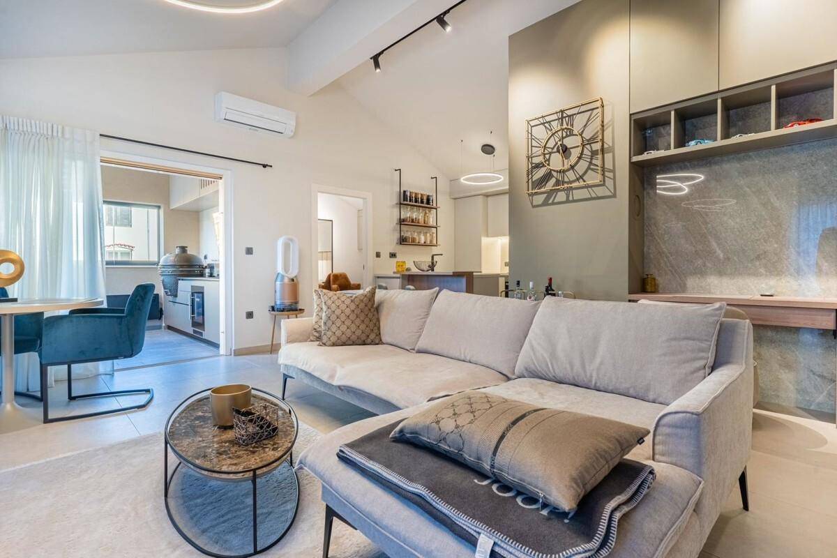 Heller offener Wohn- und Essbereich mit beigem Sofa, modernem Dekor und Blick in die Küche.