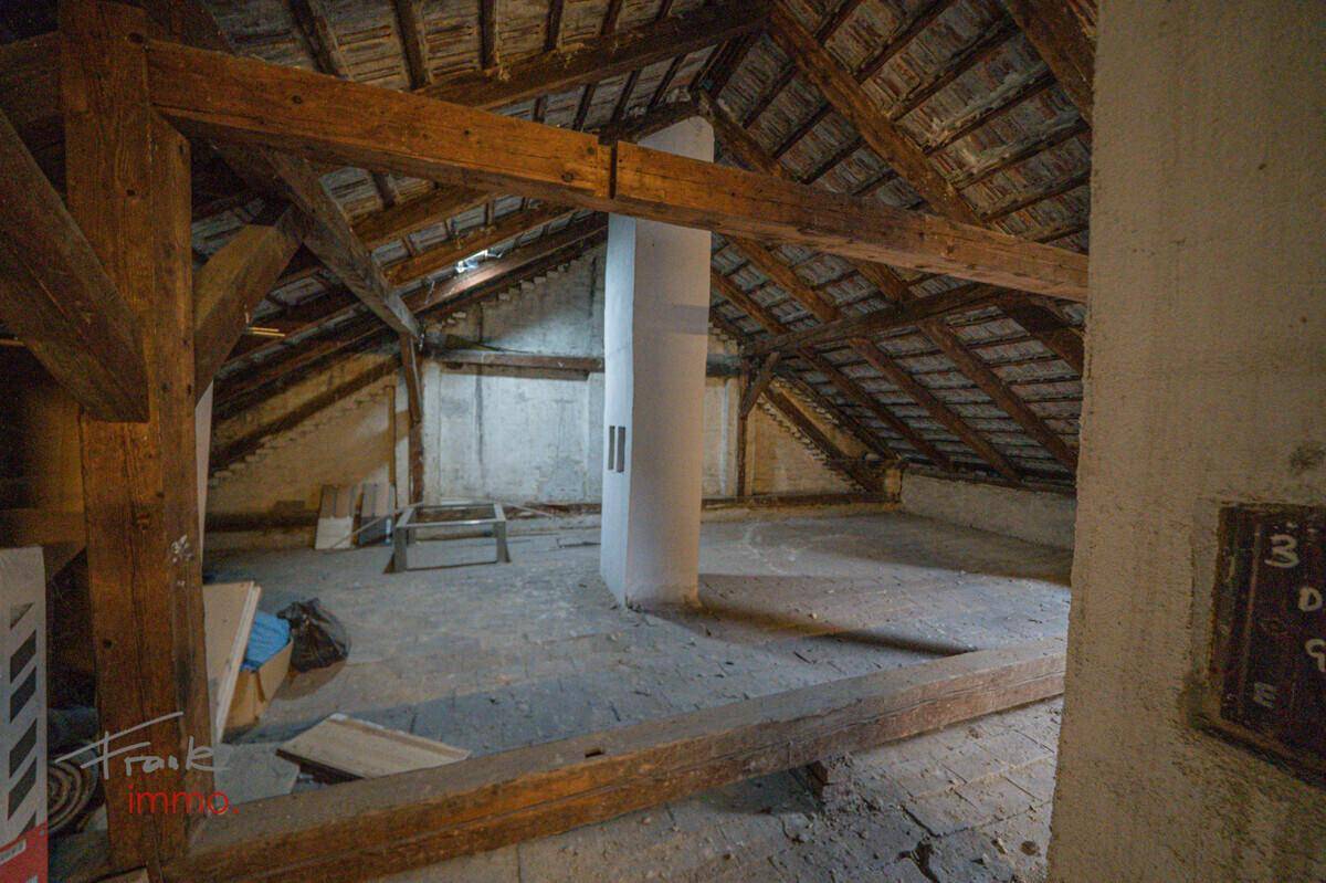 Großer Dachboden mit Holzbalken und einem zentralen Pfeiler, ideal für einen Ausbau.