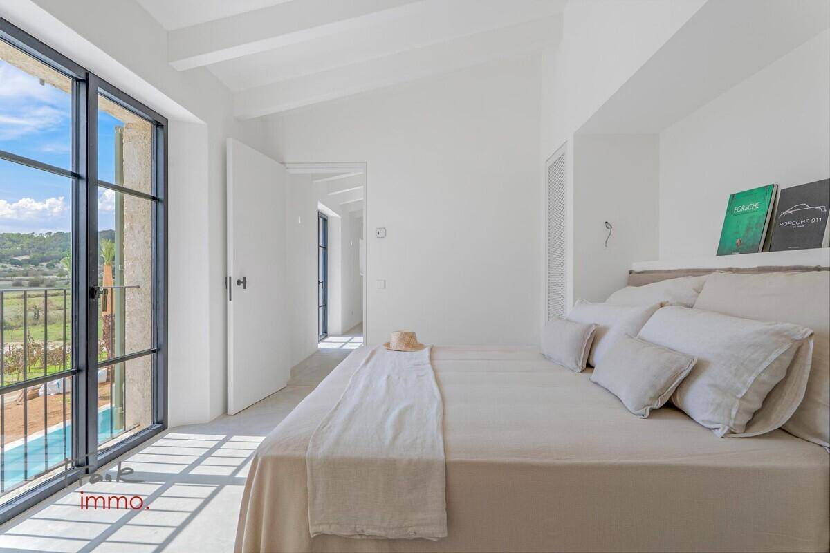 Helles Schlafzimmer mit großen Fenstern, Blick auf den Pool und die umliegende Landschaft.
