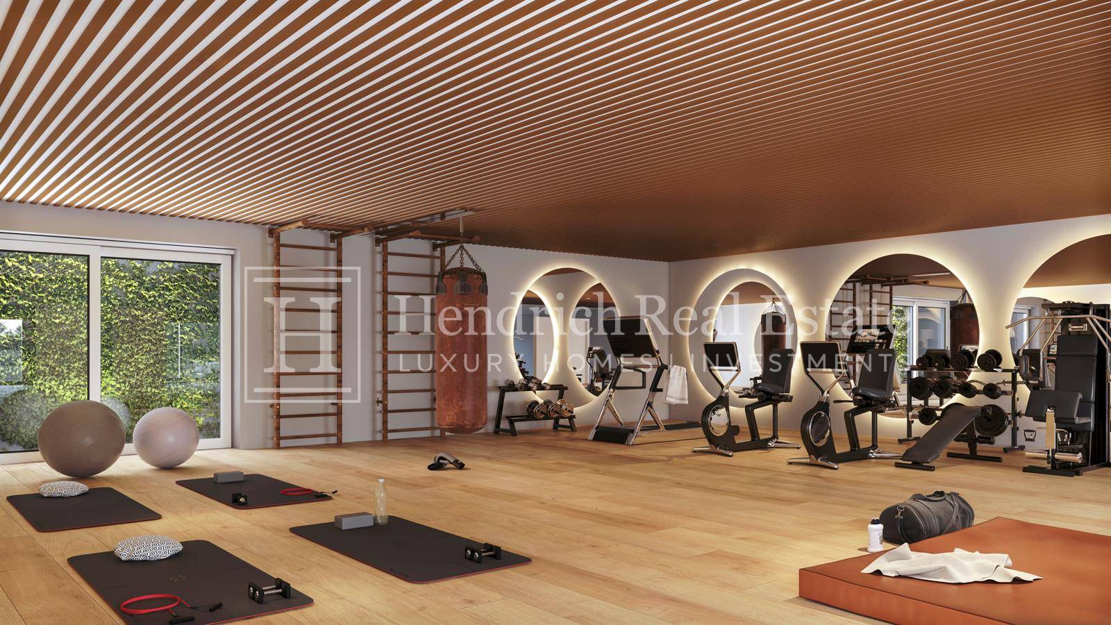 Geräumiger Fitnessraum mit Holzboden, modernen Geräten und großen Spiegeln für das Training.