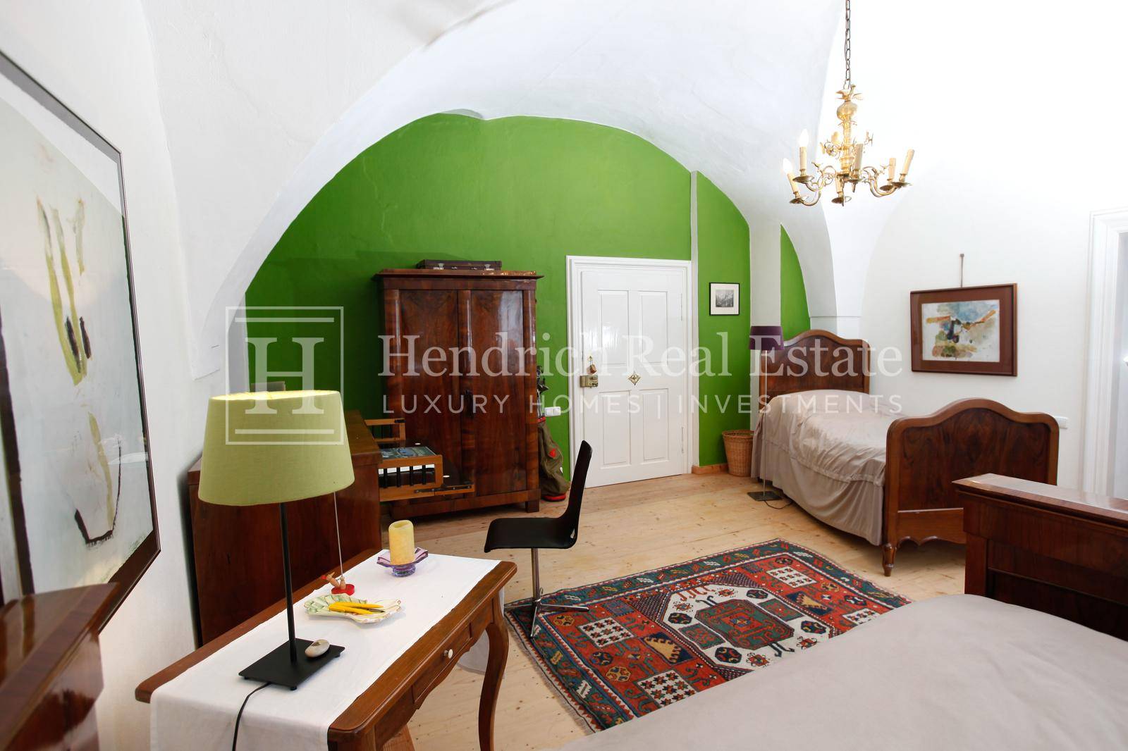 Schlafzimmer mit gewölbter Decke, grüner Akzentwand und traditionellen Holzmöbeln.