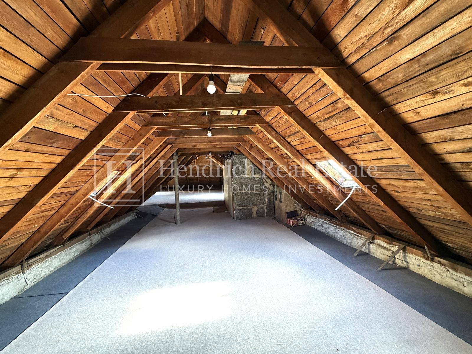 Geräumiger Dachboden mit sichtbaren Holzbalken und Dachschrägen, bereit für den Ausbau.