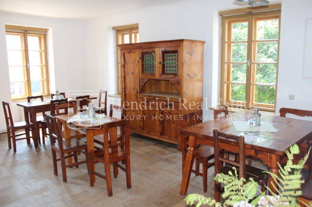 Gemütlicher Speisesaal mit traditionellen Holzmöbeln und großen Fenstern, die viel Tageslicht hereinlassen.