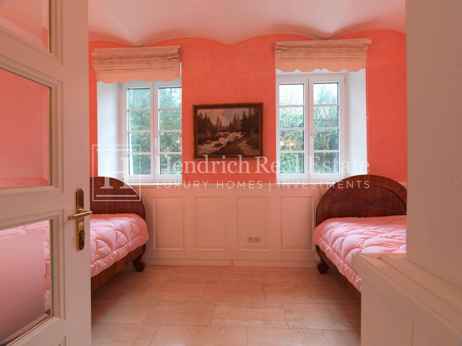 Freundliches Schlafzimmer mit zwei Einzelbetten, korallenfarbenen Wänden und zwei Fenstern.
