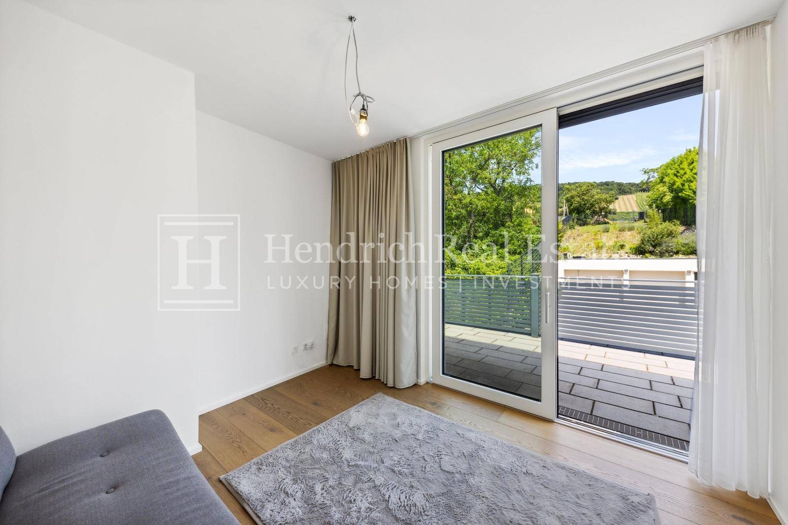 Helles Schlafzimmer mit Holzboden, großen Fenstern und direktem Zugang zur Terrasse.