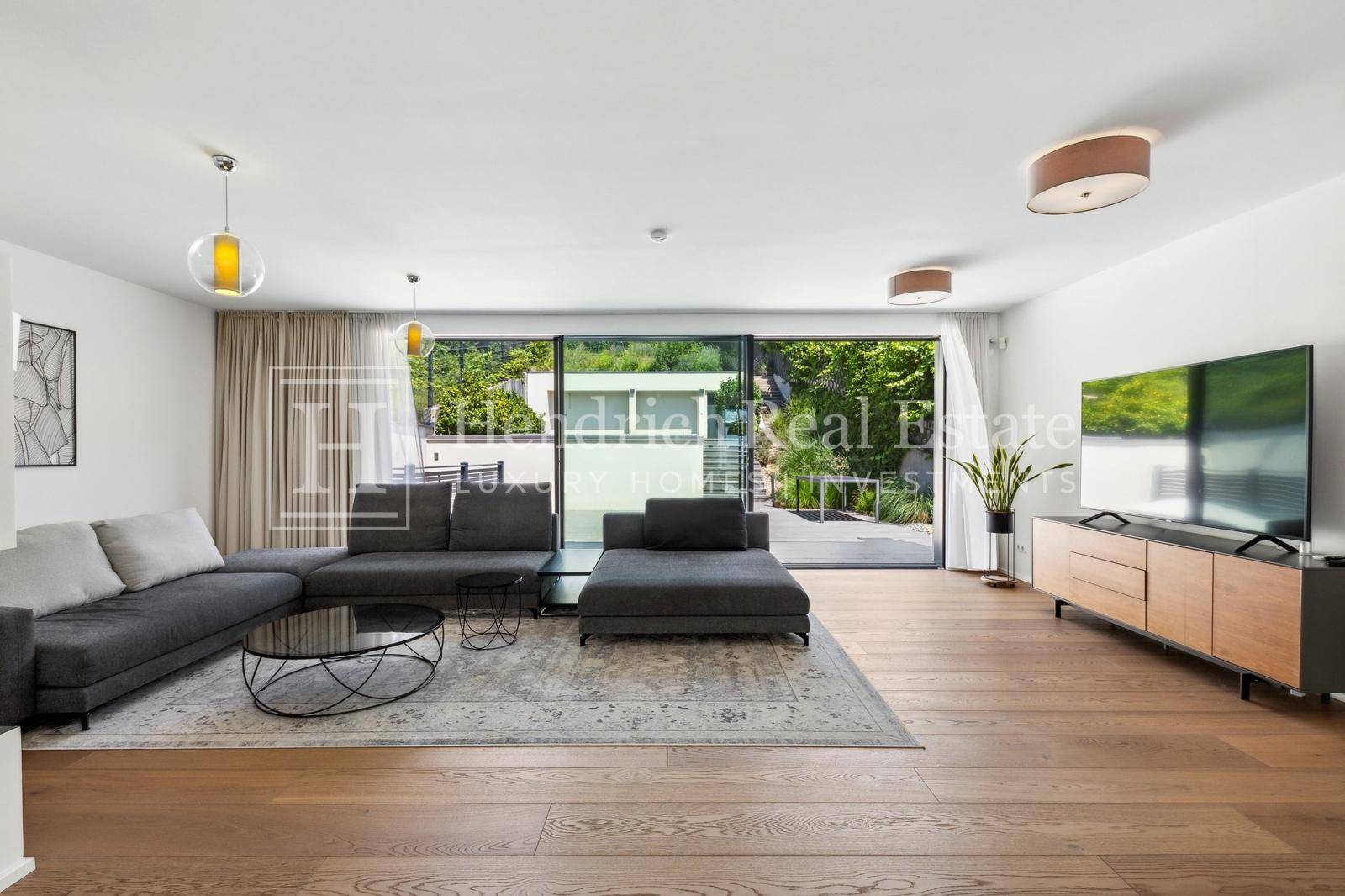 Helles Wohnzimmer mit modernem Sofa, Holzboden und großen Schiebetüren zur Terrasse.