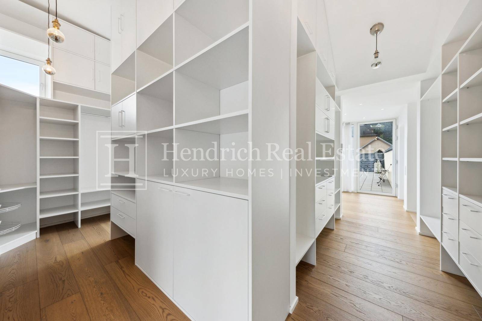 Geräumiger begehbarer Kleiderschrank mit vielen weißen Regalen und Stauraum.