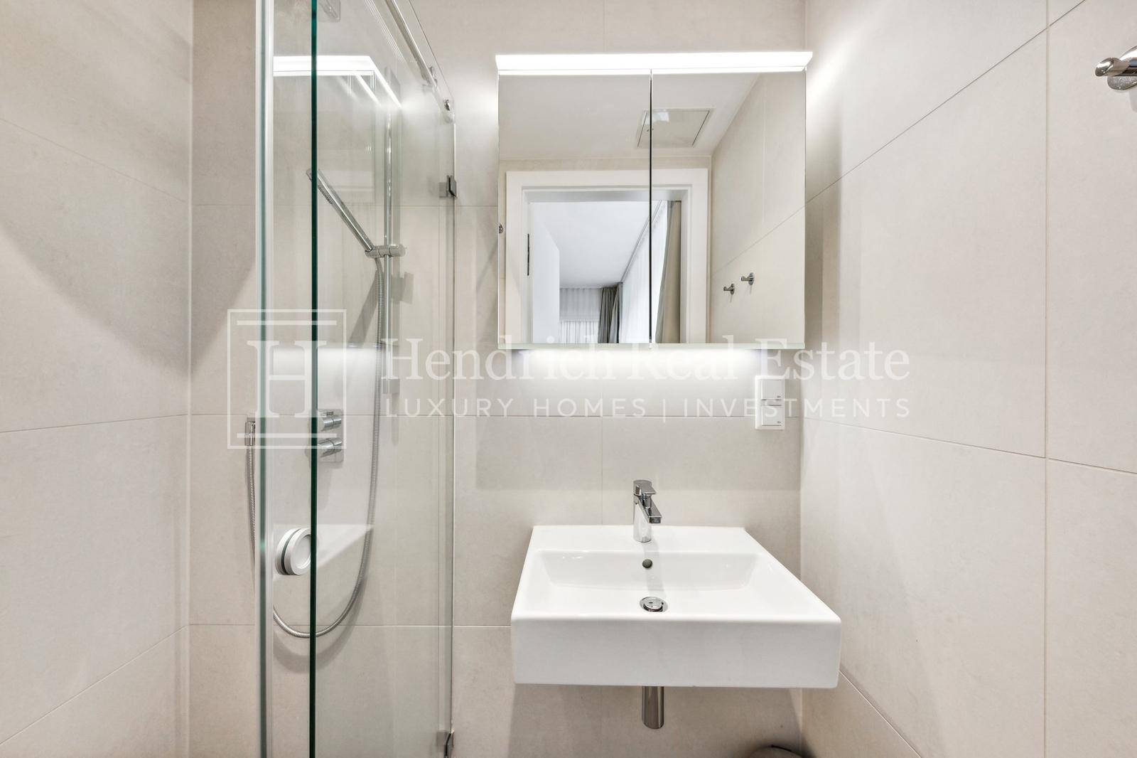 Modernes Badezimmer mit Dusche, Einzelwaschbecken und Spiegelschrank.
