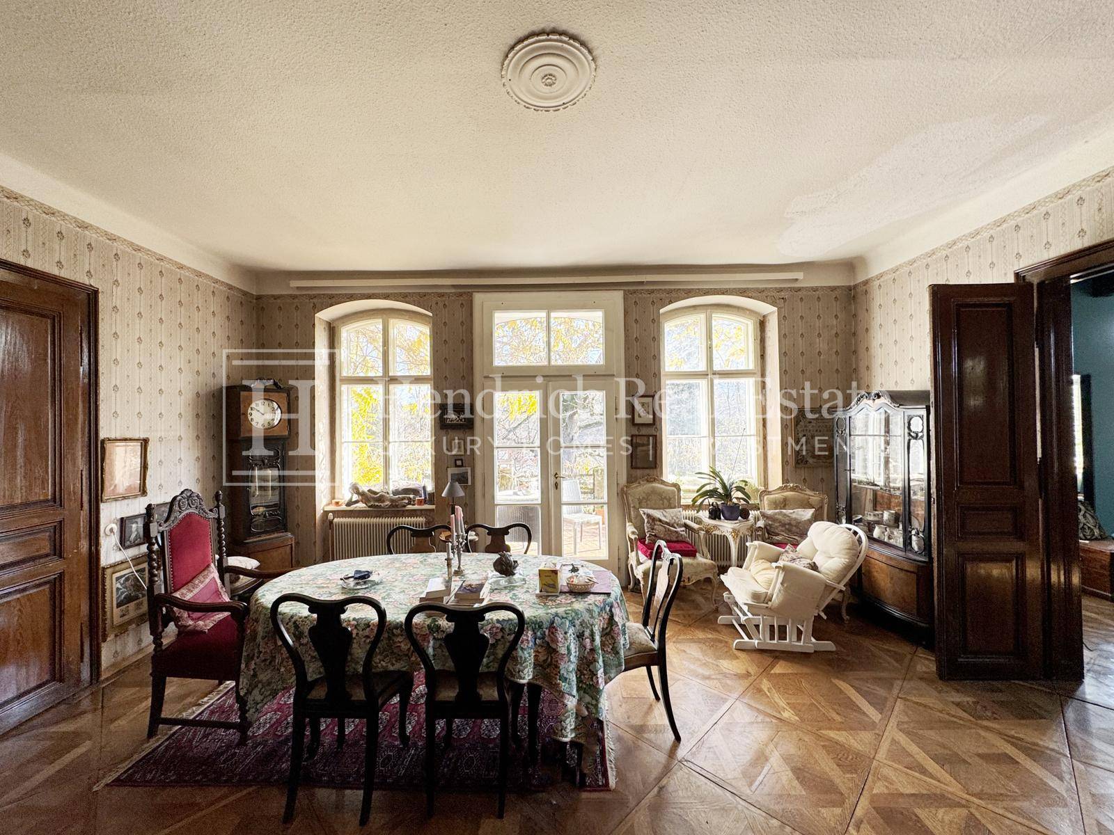 Klassisches Esszimmer mit gemusterter Tapete, Holzboden und traditionellen Möbeln, hell und einladend.