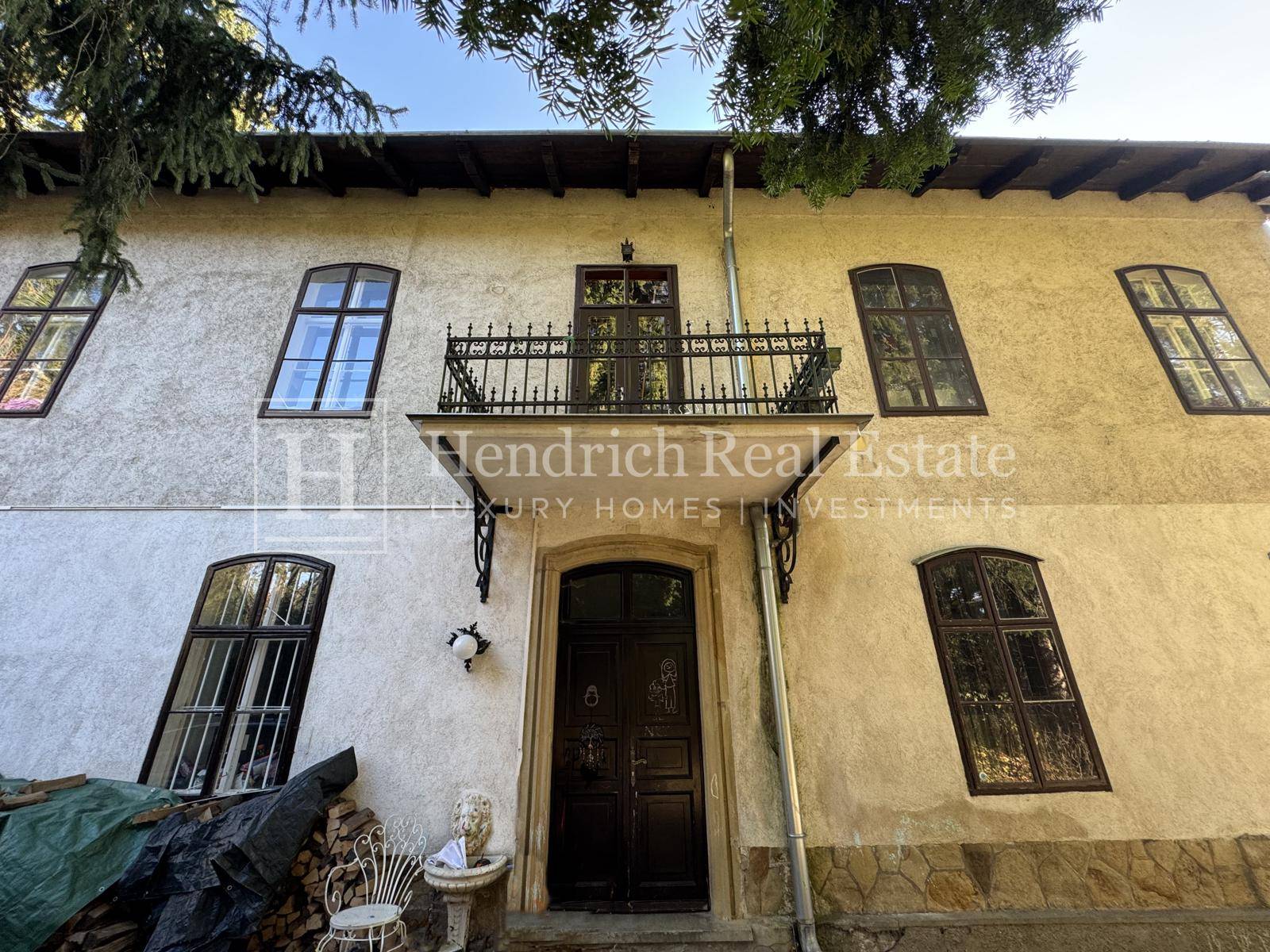 Detailansicht der Hausfassade mit Haupteingang und einem kleinen französischen Balkon darüber.