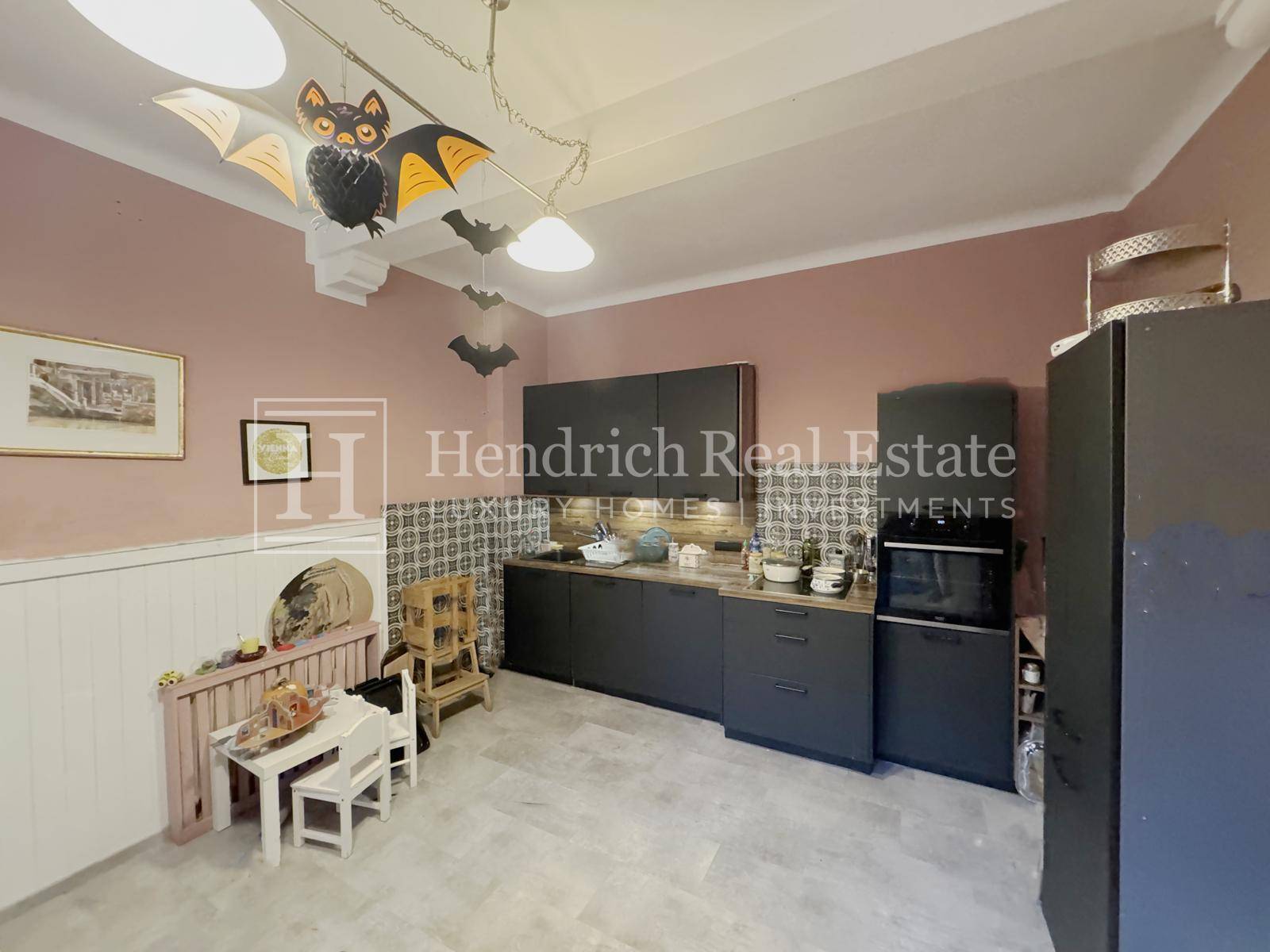 Moderne Küche mit dunkelgrauen Schränken, integriertem Backofen und hellgrauen Fliesenboden.