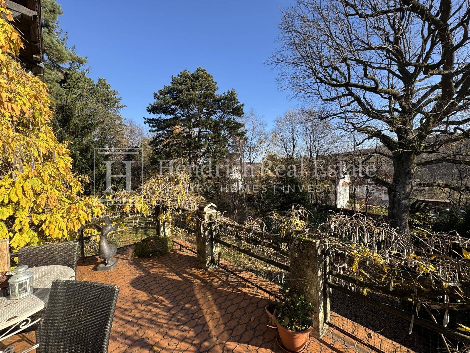 Sonniger Terrassenbereich mit Terrakottafliesen, Gartenmöbeln und Blick ins Grüne.