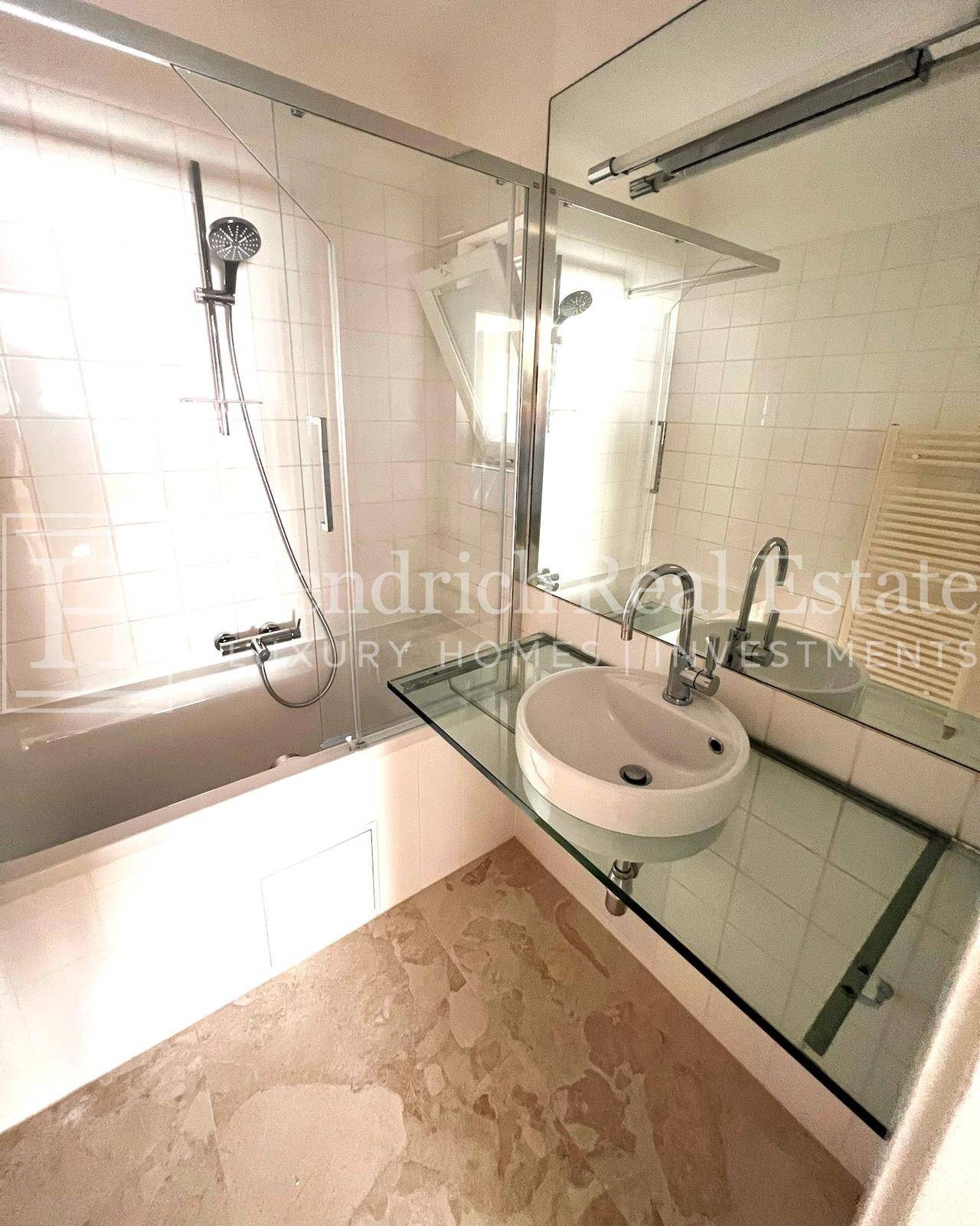 Modernes Badezimmer mit Badewanne, Duschfunktion, elegantem Waschbecken und großem Spiegel.