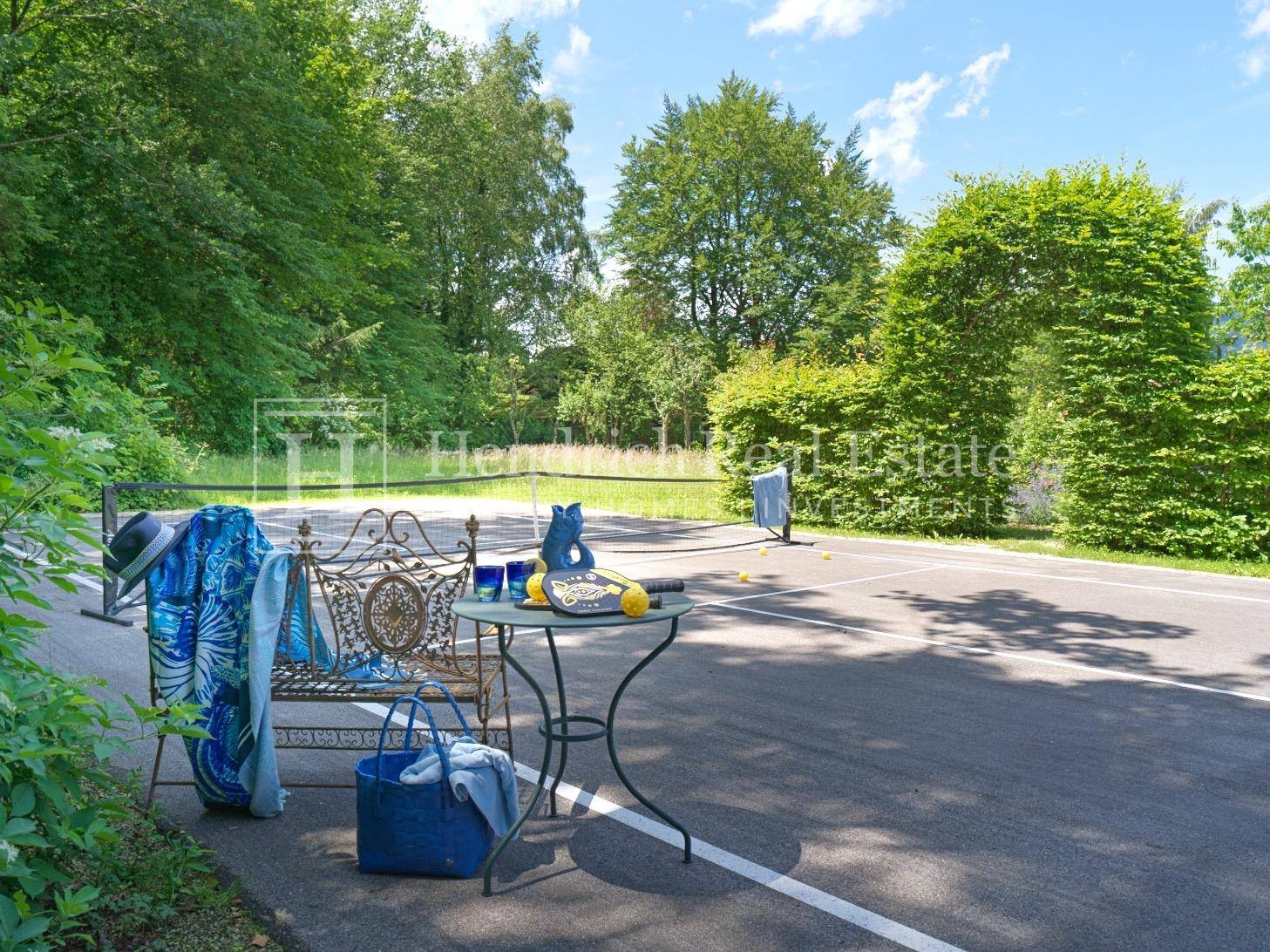 Privater Tennisplatz im Freien, umgeben von üppiger grüner Landschaft.