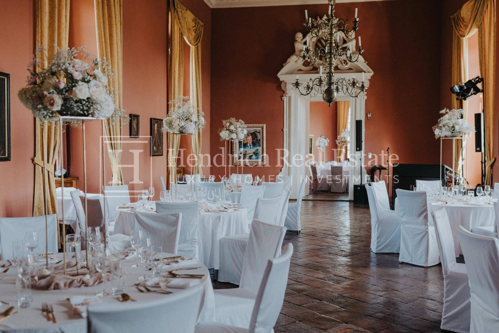 Prunkvoller Speisesaal mit festlich gedeckten Tischen, opulenten Vorhängen und einem großen Kronleuchter.