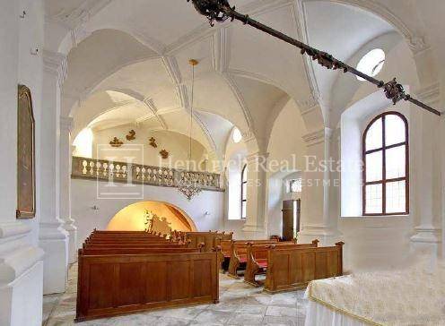 Sakraler Raum mit hohen Gewölbedecken, Kirchenbänken und einer Empore, durch Bogenfenster belichtet.