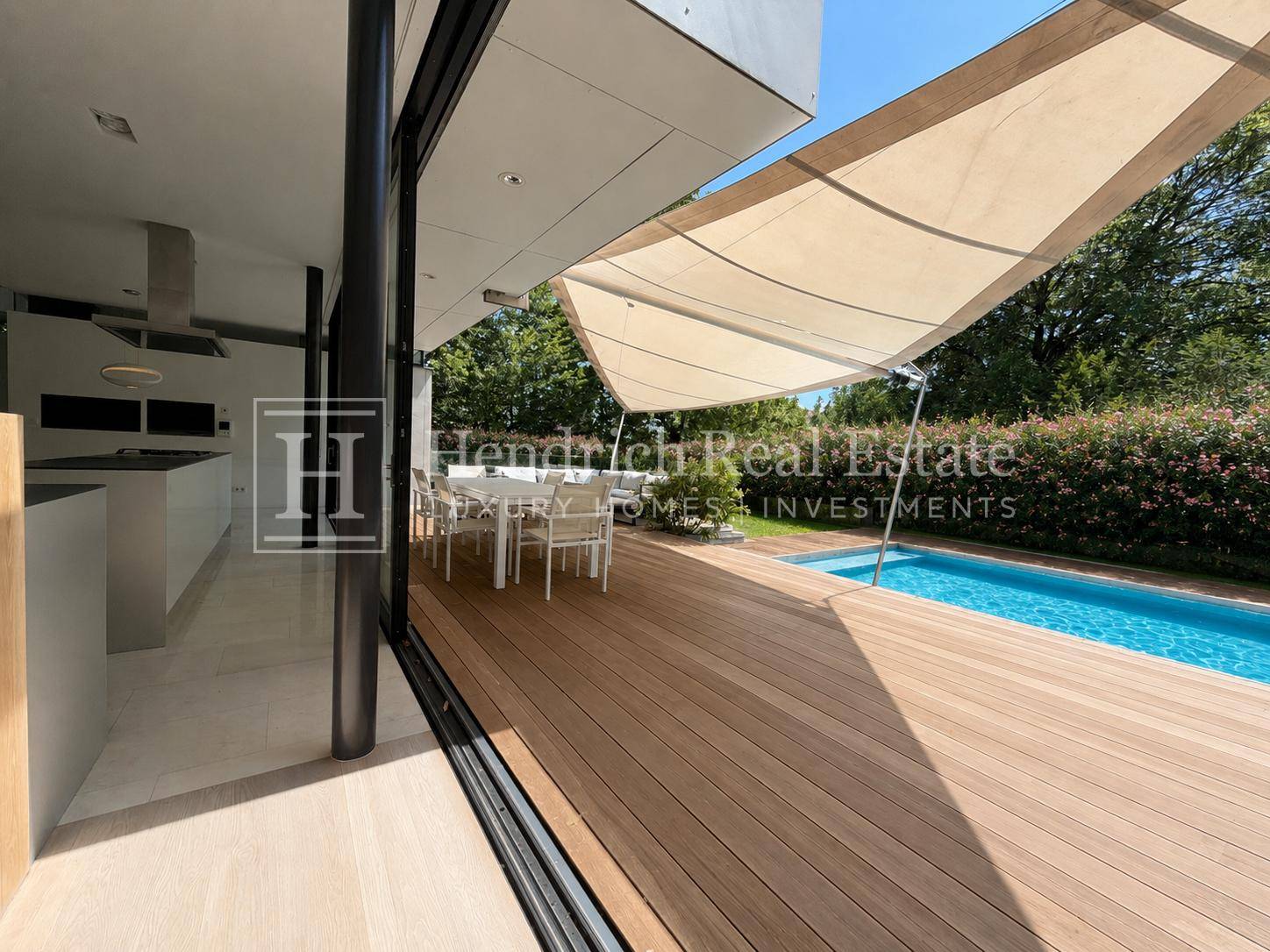 Holzterrasse mit Essbereich im Freien und Poolzugang, direkt von der Küche erreichbar.