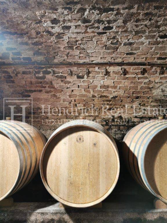 Historischer Weinkeller mit großen Holzfässern und einer rustikalen Ziegelwand, ideal zur Weinlagerung.