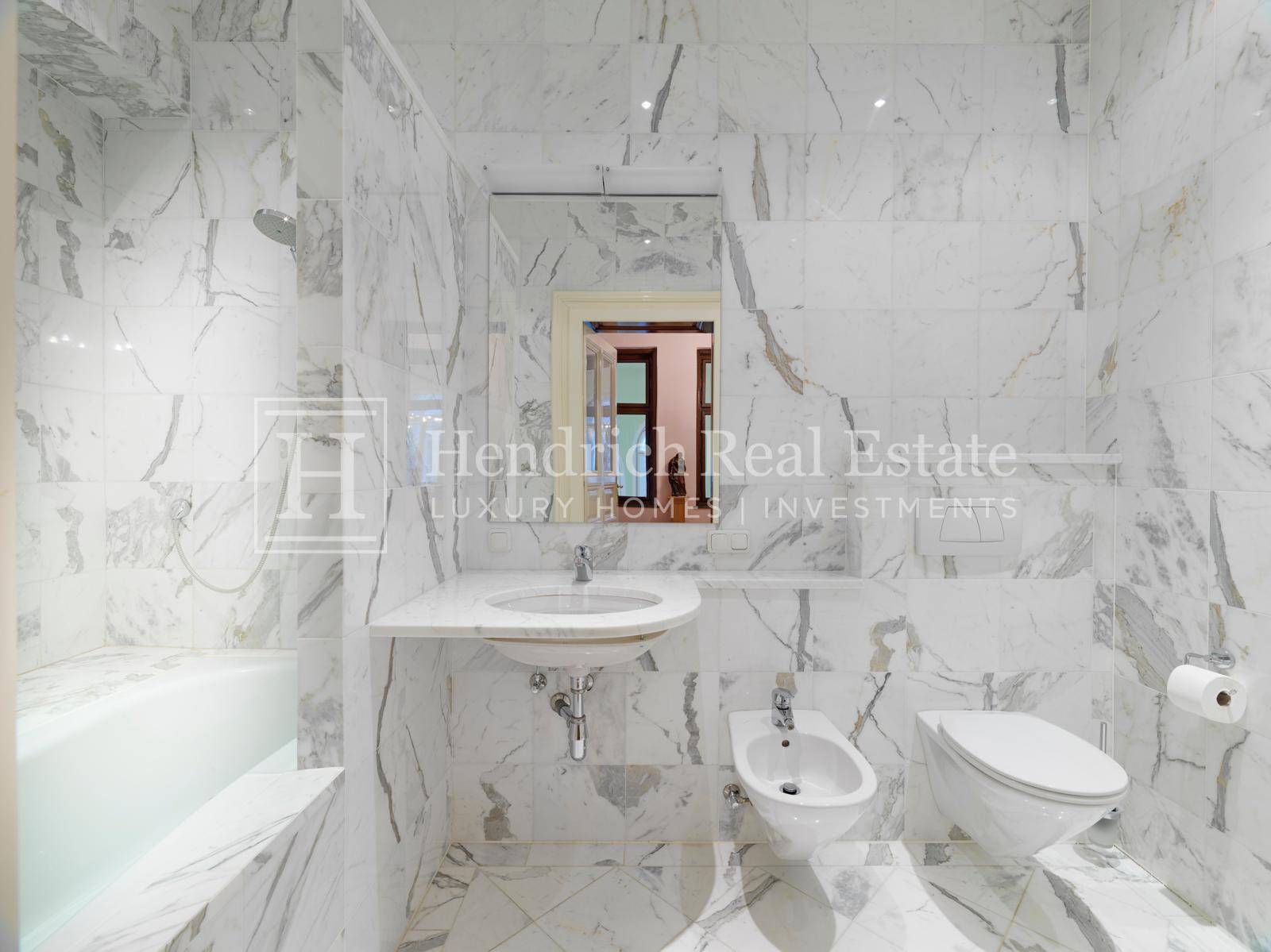 Stilvolles Badezimmer mit Marmorfliesen, Waschbecken, Bidet und Toilette.