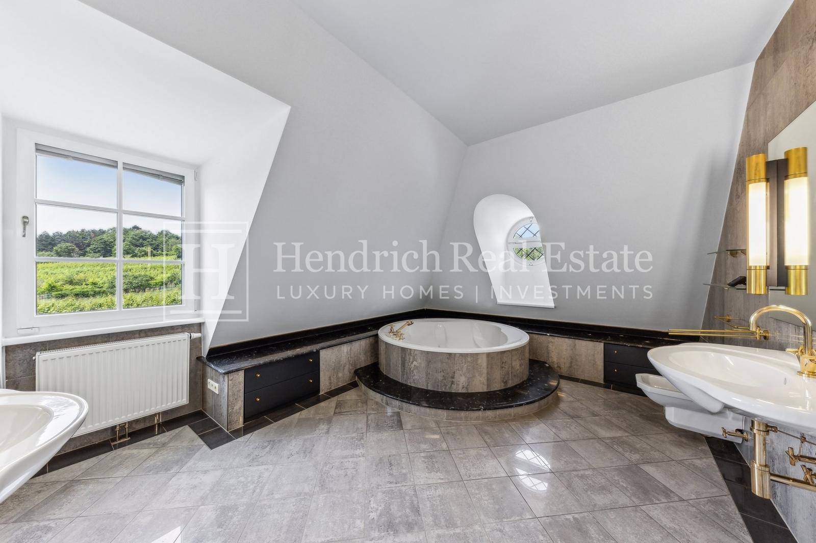 Geräumiges Badezimmer im Dachgeschoss mit runder Badewanne, Doppelwaschbecken und Landblick.