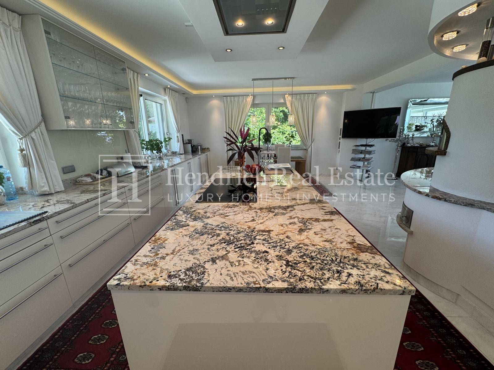 Elegante Küche mit großer Kücheninsel, Granit-Arbeitsplatten und modernen weißen Schränken.