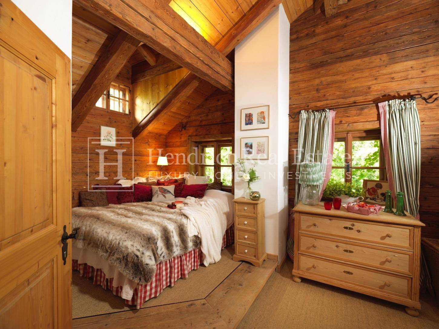 Gemütliches Dachschlafzimmer mit Holzbalken, Holzverkleidung und schrägen Decken.