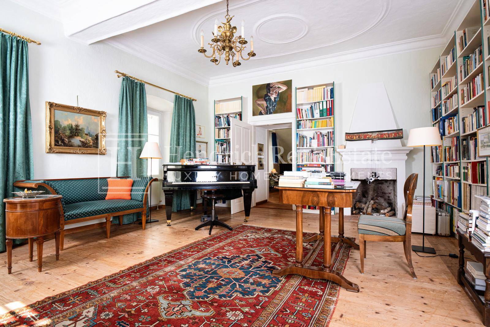 Geräumiges Wohnzimmer mit Flügel, Bücherregalen, Kamin und Holzdielenboden.