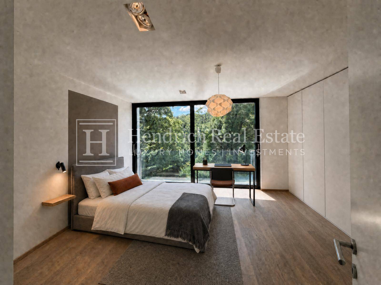 Helles Schlafzimmer mit Bett, Schreibtisch und großem Fenster mit Blick auf die Natur.
