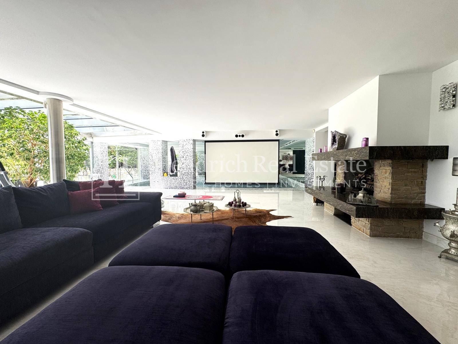 Moderner Medienraum mit großem Projektionsbildschirm, bequemen Sofas und elegantem Kamin.