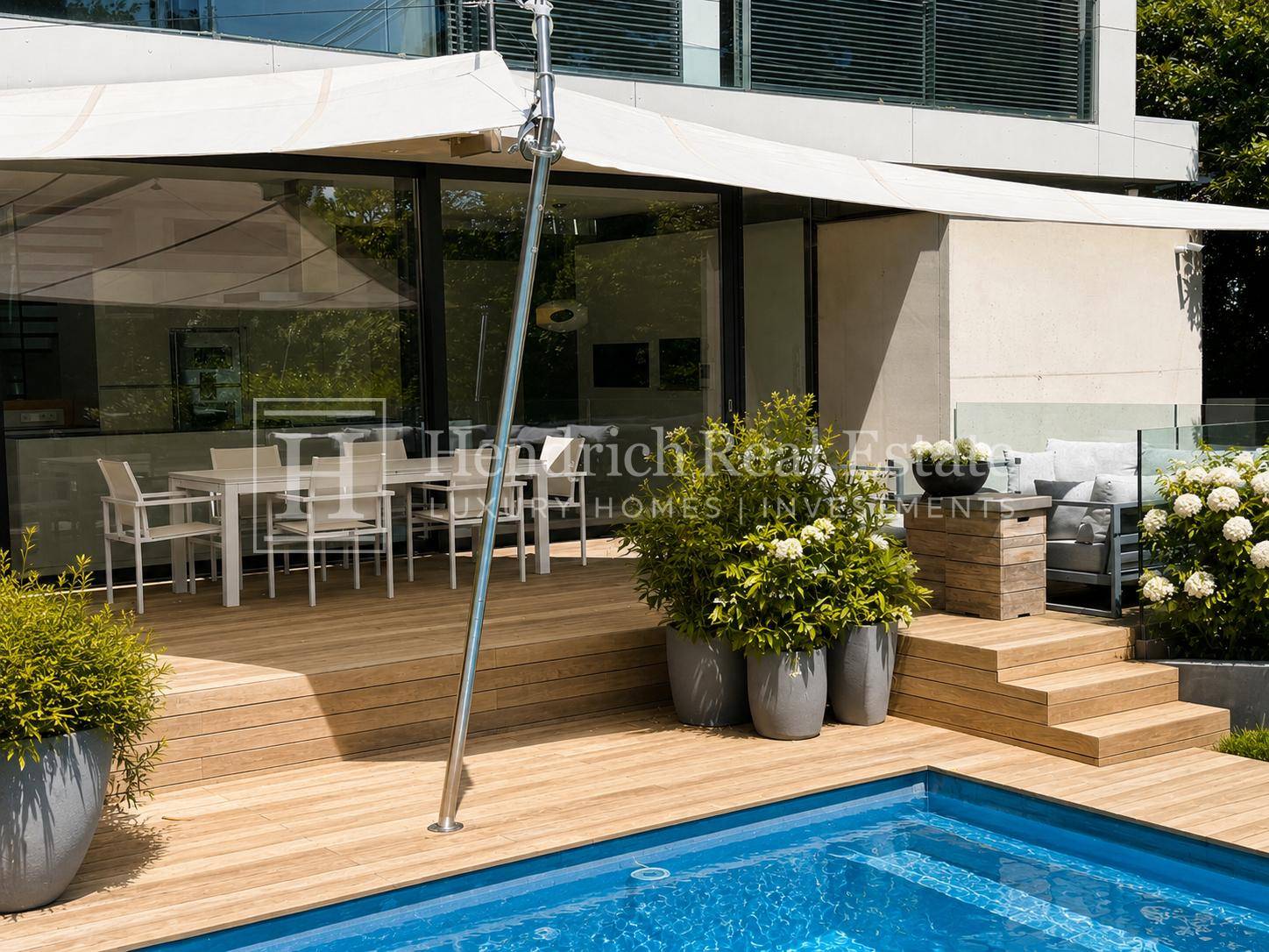 Großzügige Holzterrasse mit Essbereich und Lounge-Möbeln direkt am erfrischenden Pool.