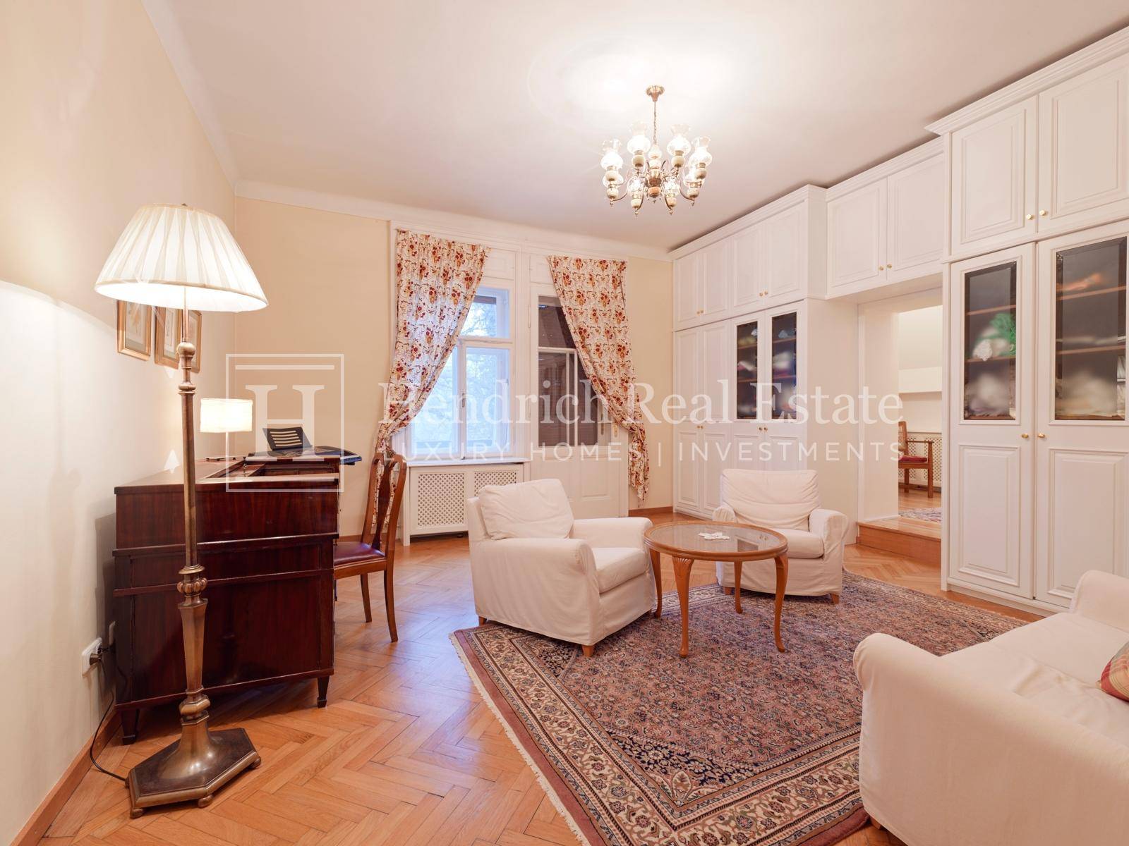 Elegantes Arbeitszimmer mit Einbauschränken, bequemen Sesseln und Parkettboden.