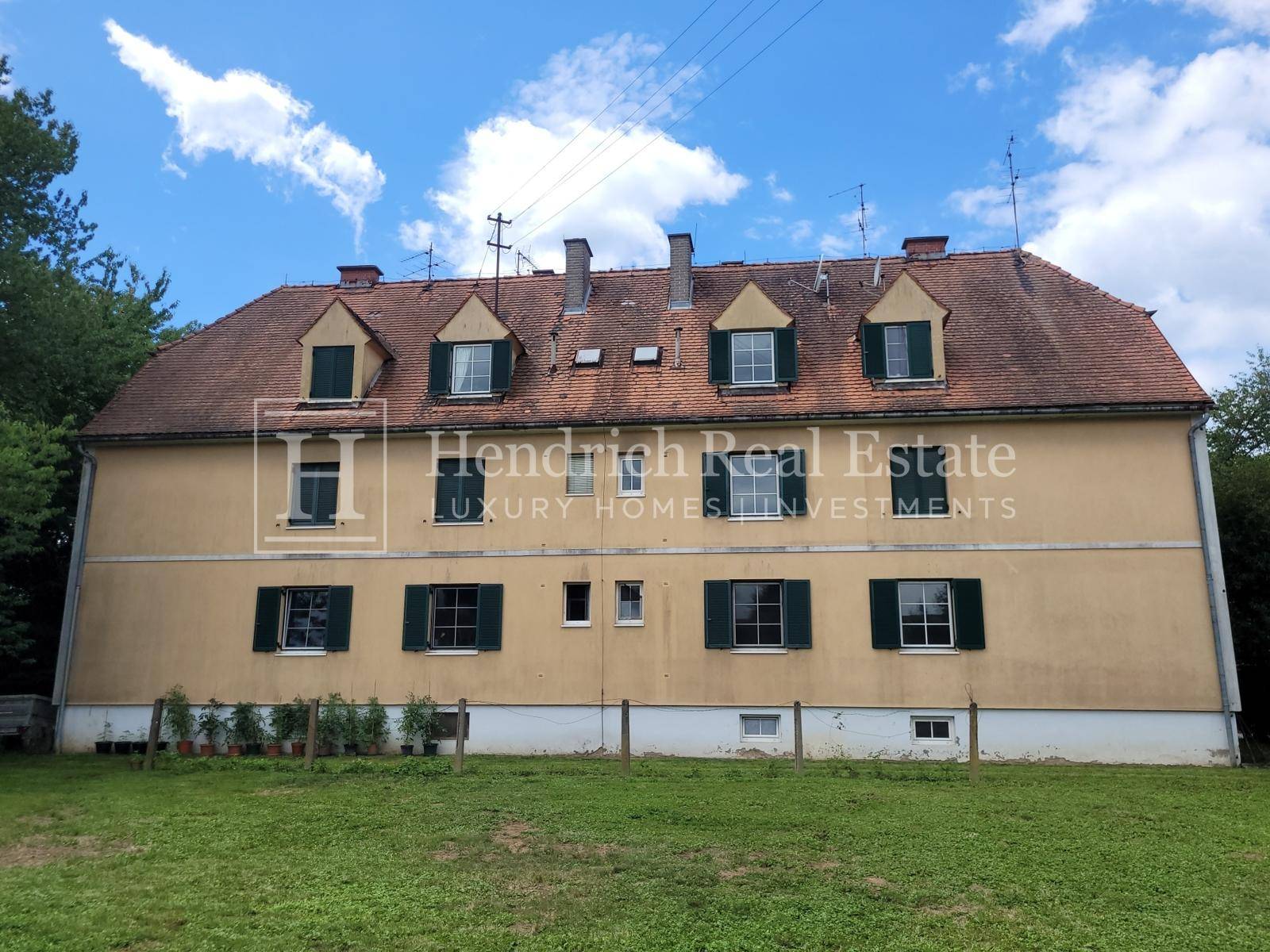 Rückansicht des historischen Gebäudes mit weitläufigem Rasen und Blick ins Grüne.