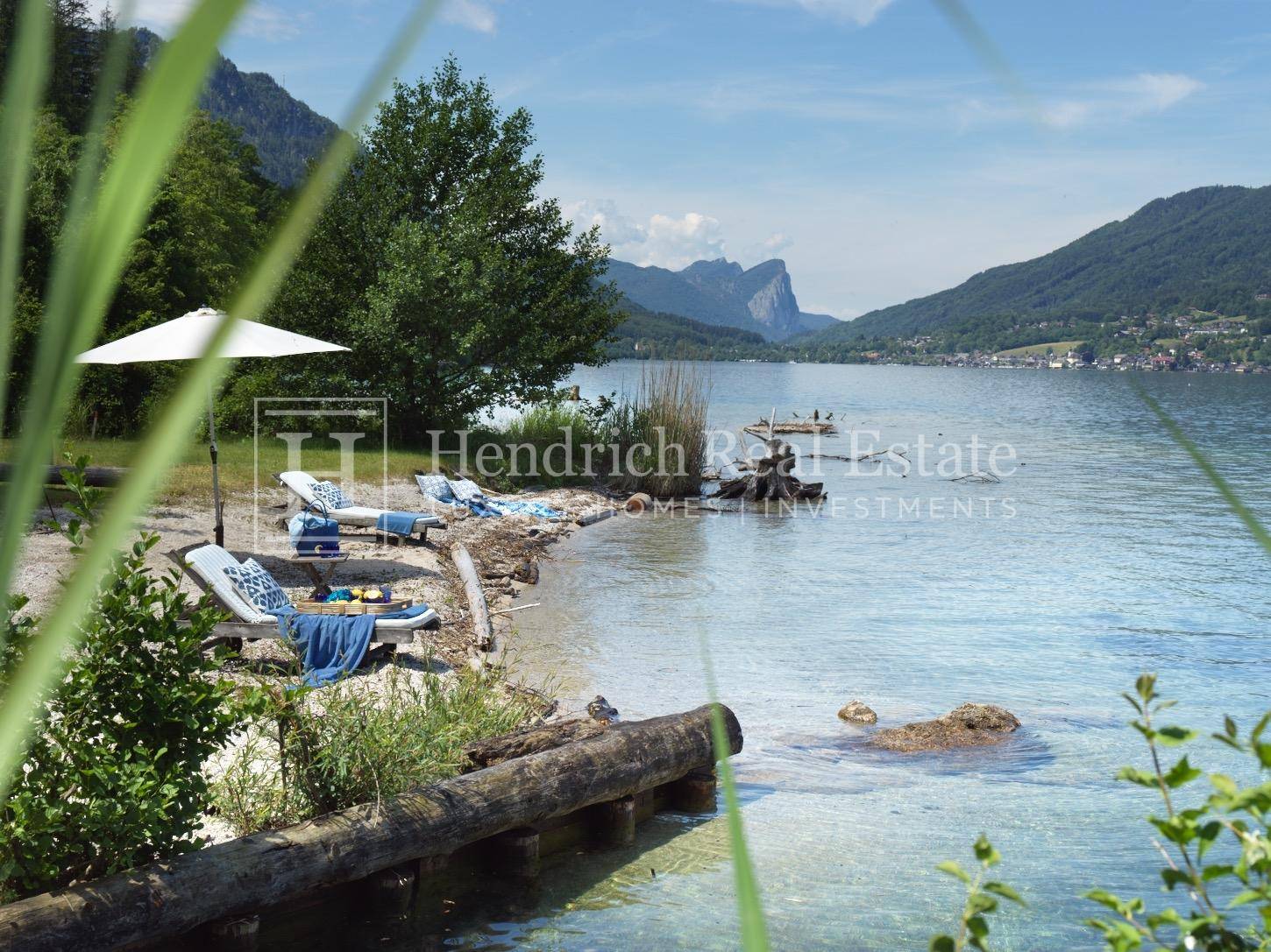 Privater Seezugang mit Liegestühlen am Ufer und malerischem Bergpanorama.