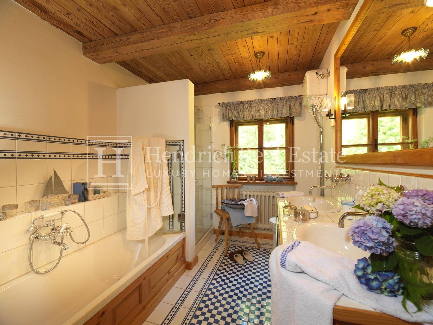 Helles Badezimmer mit Badewanne, Dusche, Doppelwaschbecken und karierten Fliesen.