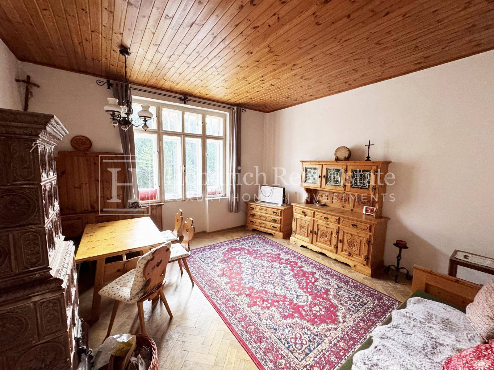 Gemütlicher Raum mit Holztäfelung an der Decke, traditionellen Holzmöbeln und einem großen Fenster.