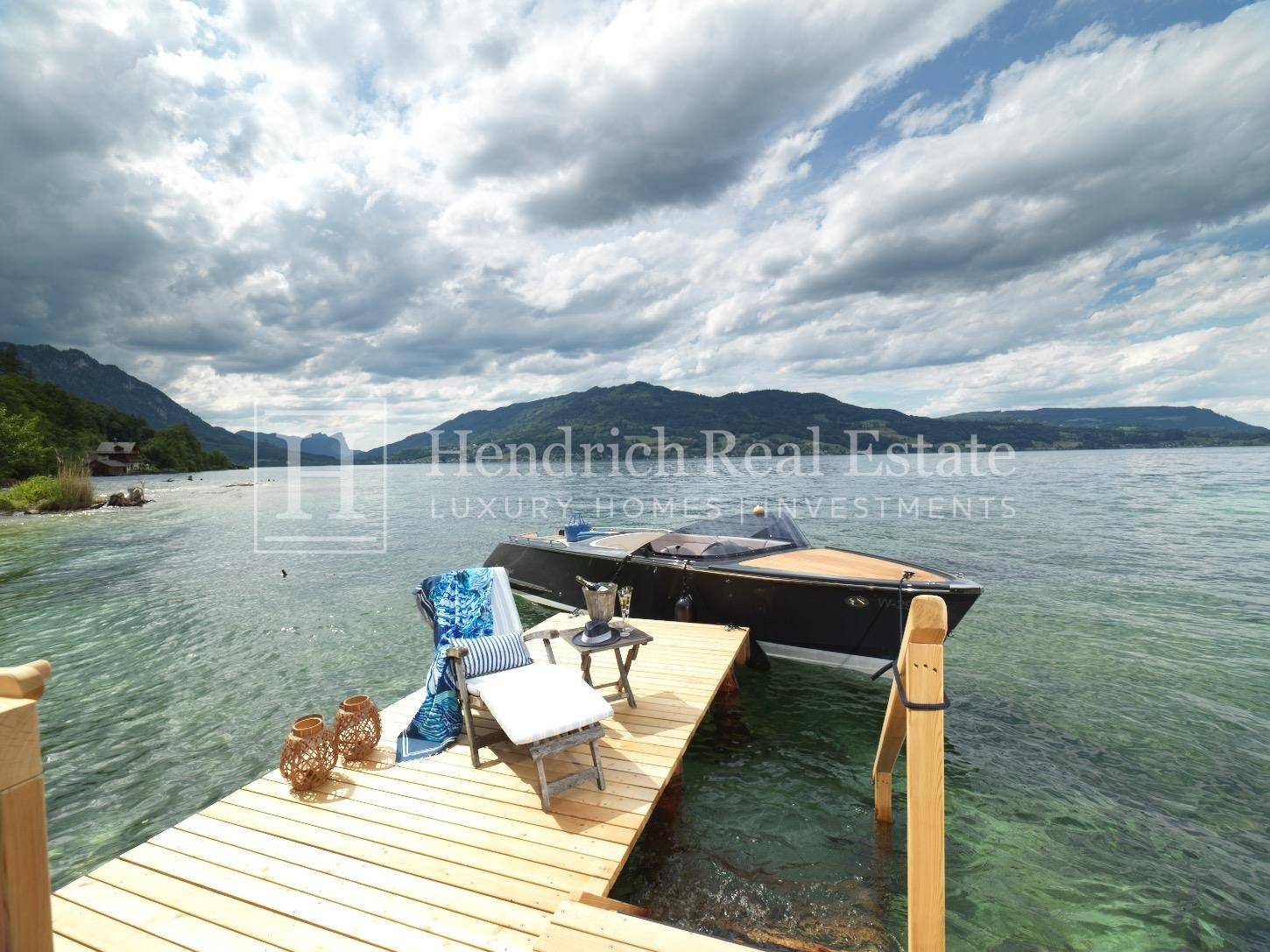 Privater Bootssteg am See mit Motorboot und malerischem Bergpanorama.