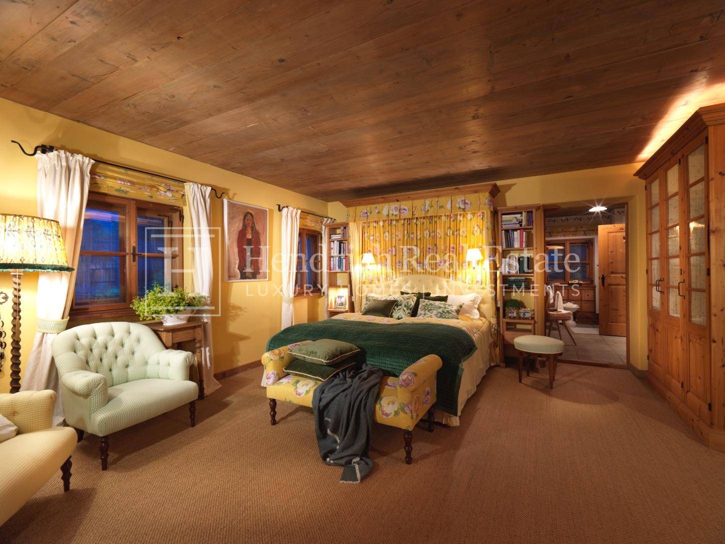 Gemütliches Schlafzimmer mit Doppelbett, gelben Wänden und Holzbalkendecke.